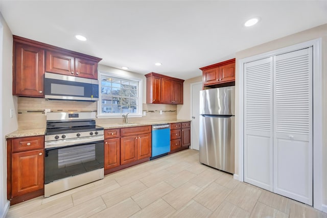 kitchen featuring sink, decorative backsplash, light stone countertops, and appliances with stainless steel finishes