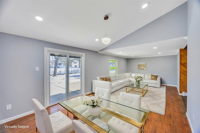 dining area with a baseboard radiator, wood-type flooring, and vaulted ceiling