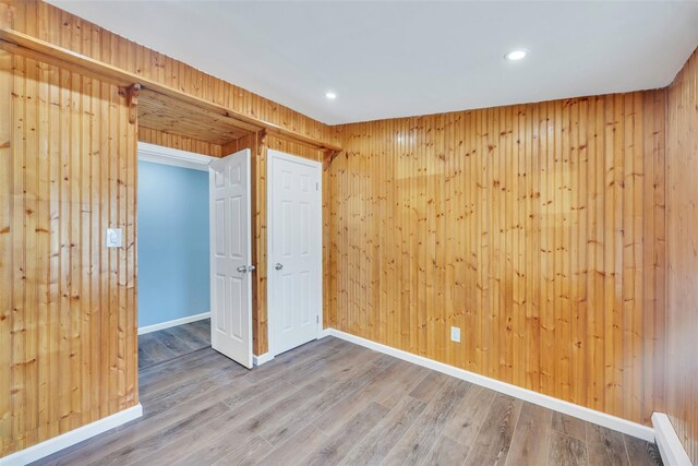 unfurnished room featuring wooden walls and wood-type flooring