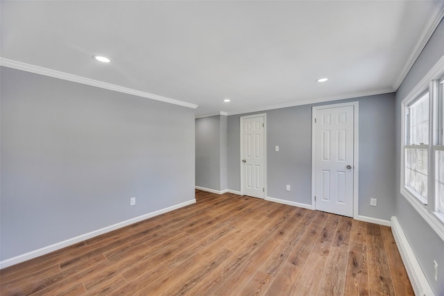 spare room with crown molding and light wood-type flooring