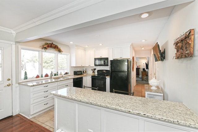 kitchen featuring white cabinetry, sink, backsplash, light stone counters, and black appliances