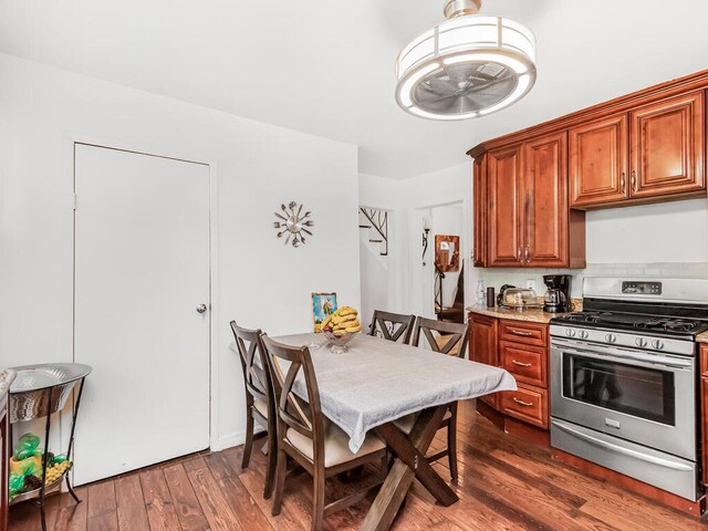 kitchen with light stone counters, stainless steel range with gas stovetop, and dark hardwood / wood-style flooring