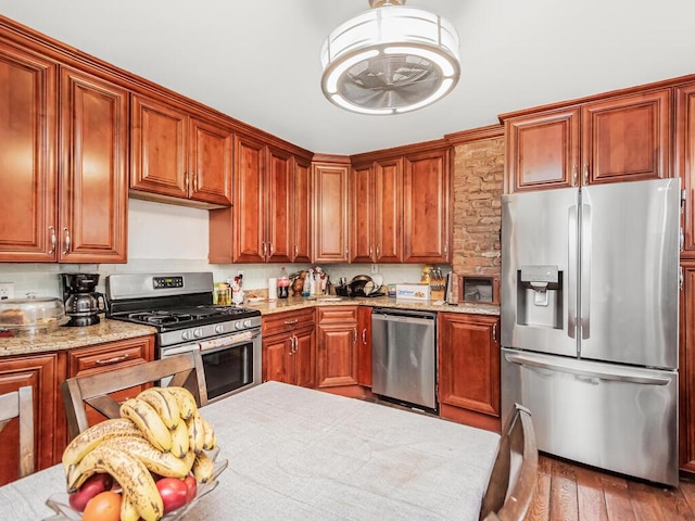 kitchen with stainless steel appliances, light stone countertops, and light hardwood / wood-style flooring