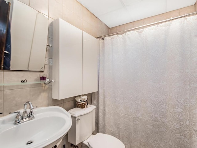 bathroom featuring toilet, sink, a shower with curtain, tile walls, and backsplash