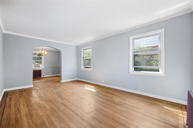 empty room with radiator, a notable chandelier, ornamental molding, and a healthy amount of sunlight