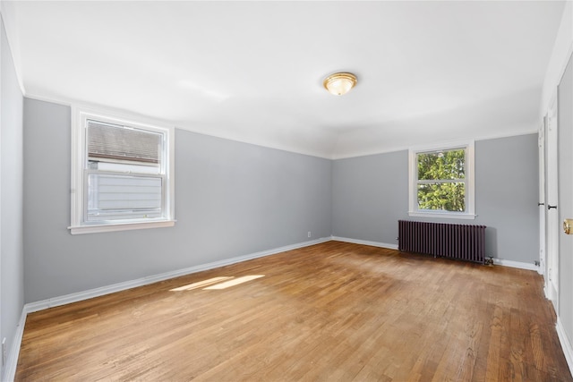 empty room with hardwood / wood-style floors and radiator heating unit