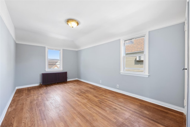 spare room with radiator, hardwood / wood-style flooring, and vaulted ceiling