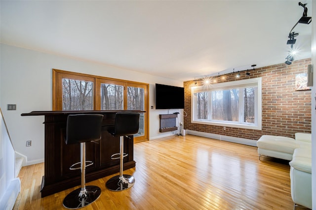 living room featuring a baseboard radiator, brick wall, and wood-type flooring