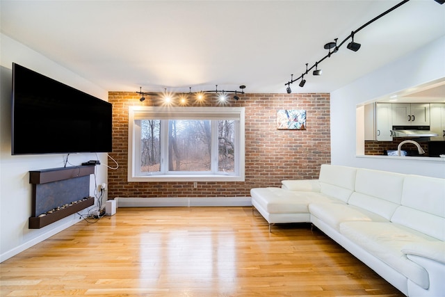 living room with brick wall and light wood-type flooring