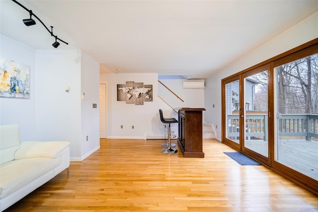 interior space featuring track lighting, a wall unit AC, light hardwood / wood-style floors, and french doors