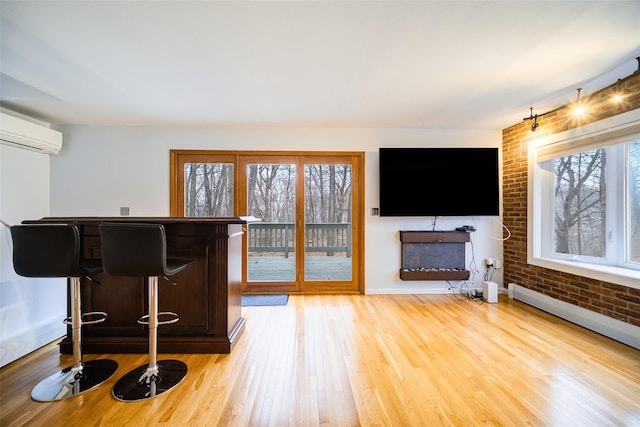 interior space with brick wall, a wall unit AC, bar, and light wood-type flooring