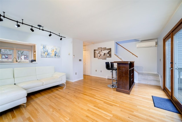 living room with rail lighting, a wall mounted AC, and light hardwood / wood-style floors