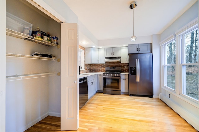 kitchen featuring sink, decorative light fixtures, light hardwood / wood-style flooring, appliances with stainless steel finishes, and gray cabinets