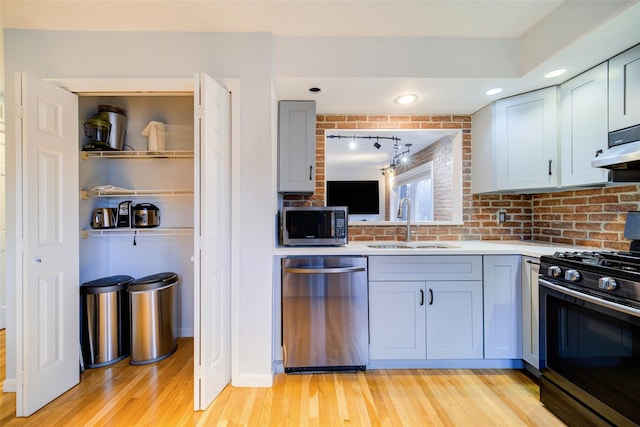 kitchen with sink, stainless steel appliances, and light hardwood / wood-style floors