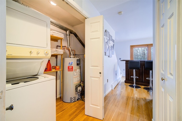 washroom with indoor bar, stacked washer and clothes dryer, water heater, and light hardwood / wood-style flooring