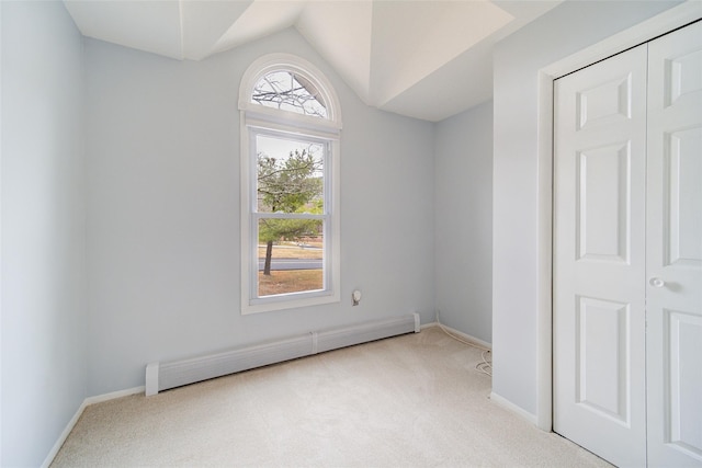 empty room with lofted ceiling, light colored carpet, and baseboard heating