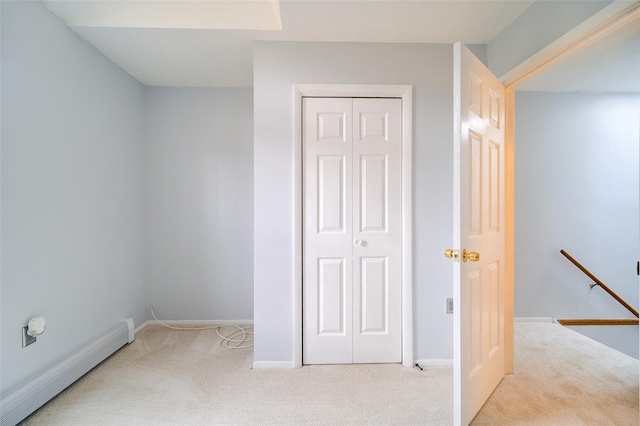 interior space featuring a baseboard heating unit, light colored carpet, and a closet