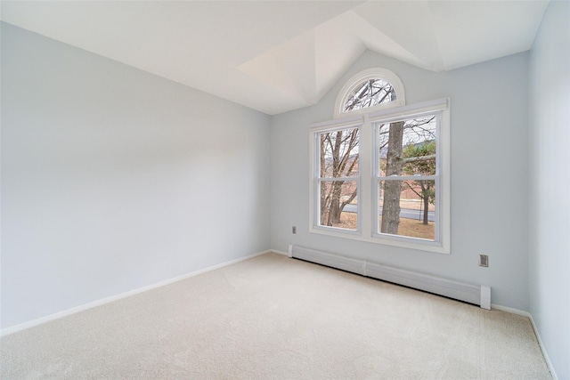 empty room featuring lofted ceiling, a baseboard heating unit, and light colored carpet