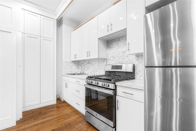 kitchen featuring appliances with stainless steel finishes, sink, wood-type flooring, and white cabinets