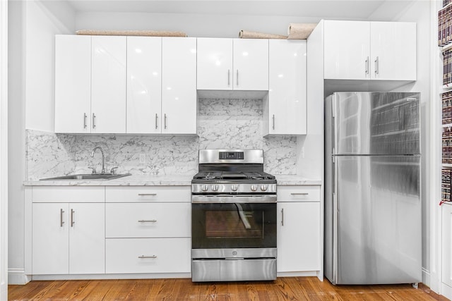 kitchen featuring sink, white cabinetry, tasteful backsplash, appliances with stainless steel finishes, and light stone countertops