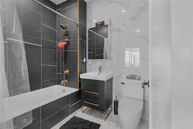 full bathroom featuring vanity, toilet, tiled shower / bath combo, and tile walls