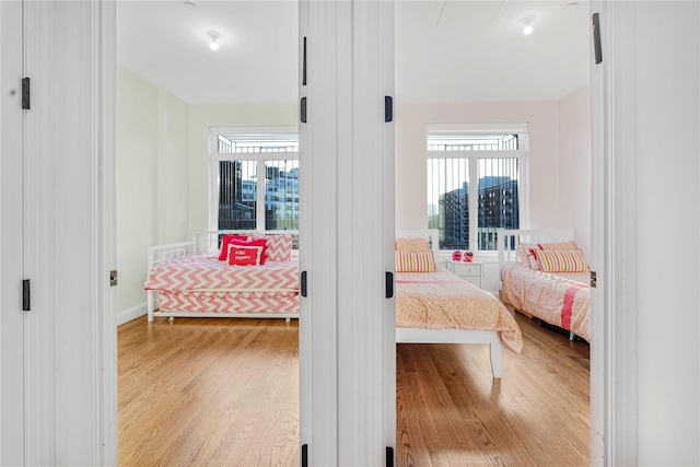 bedroom with multiple windows and light hardwood / wood-style flooring