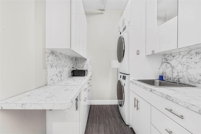 clothes washing area with sink, cabinets, and stacked washer / dryer