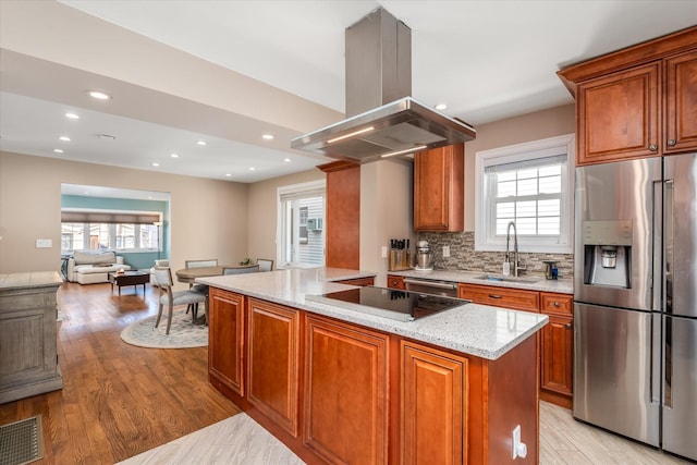 kitchen with sink, light hardwood / wood-style flooring, appliances with stainless steel finishes, light stone counters, and island range hood