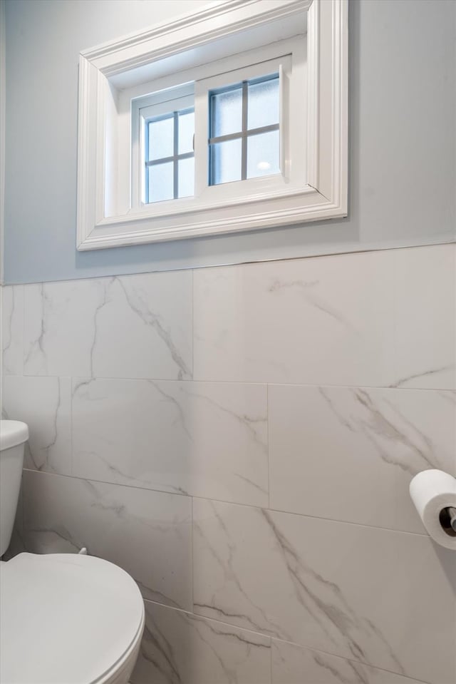 bathroom featuring tile walls and toilet