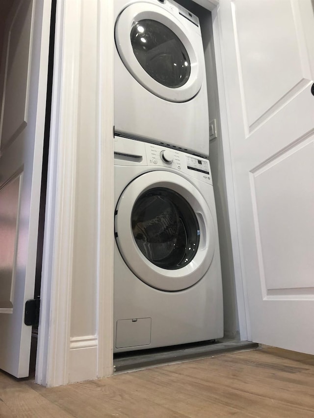 laundry area featuring light hardwood / wood-style flooring and stacked washing maching and dryer