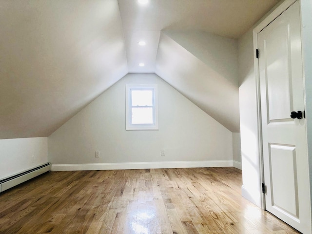 additional living space with baseboard heating, wood-type flooring, and vaulted ceiling