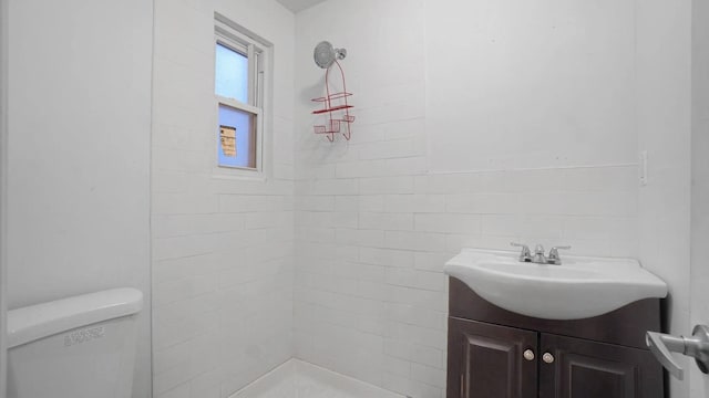 bathroom with vanity, a tile shower, and toilet