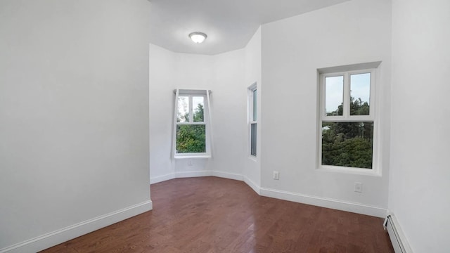 empty room featuring a baseboard radiator and dark hardwood / wood-style flooring