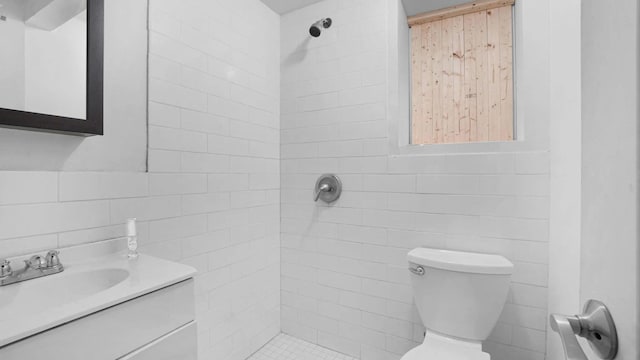 bathroom with vanity, toilet, tile walls, and a tile shower