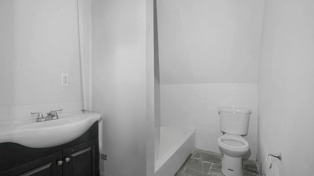 bathroom featuring vanity, a bath, and toilet