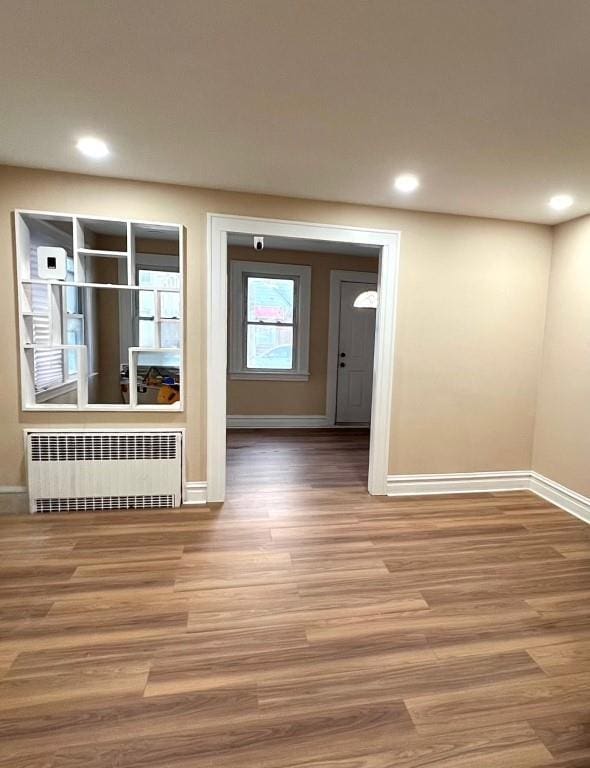 empty room with hardwood / wood-style floors and radiator heating unit