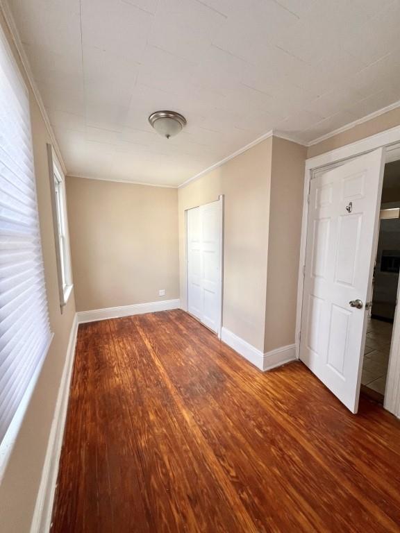 unfurnished bedroom featuring dark wood-type flooring and ornamental molding