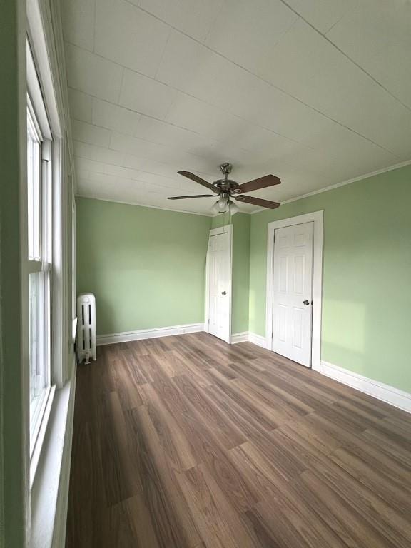 spare room featuring ornamental molding, a healthy amount of sunlight, dark hardwood / wood-style flooring, and radiator