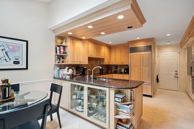 kitchen featuring tasteful backsplash, sink, dark stone countertops, kitchen peninsula, and paneled fridge