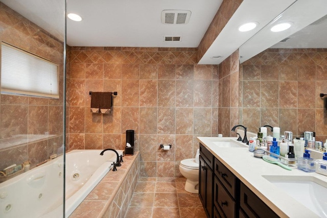 bathroom featuring a relaxing tiled tub, vanity, toilet, and tile walls