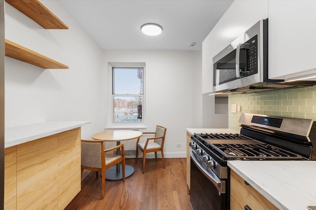 kitchen with appliances with stainless steel finishes, dark hardwood / wood-style floors, white cabinets, decorative backsplash, and light stone counters