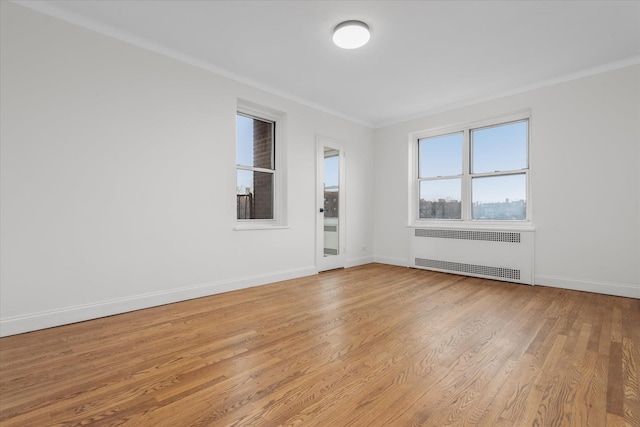 unfurnished room with ornamental molding, radiator, and light wood-type flooring