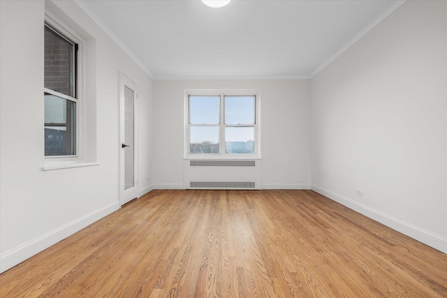 empty room featuring ornamental molding, radiator heating unit, and light wood-type flooring