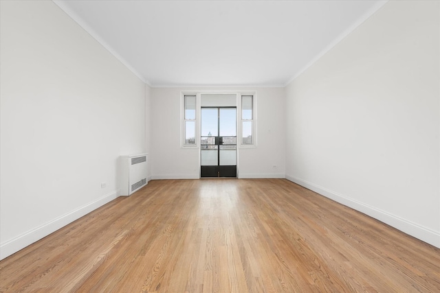 unfurnished room with radiator, light wood finished floors, baseboards, and ornamental molding