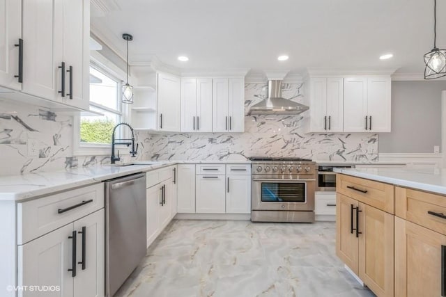 kitchen featuring sink, appliances with stainless steel finishes, white cabinets, decorative light fixtures, and wall chimney exhaust hood