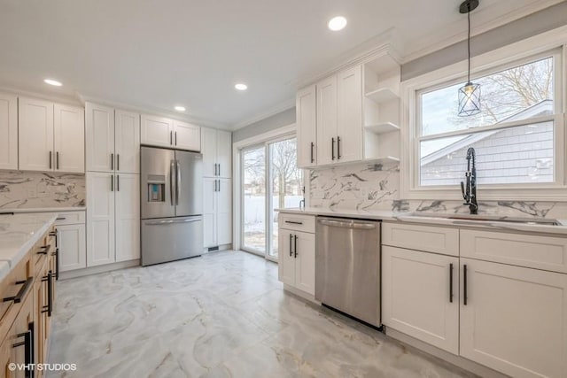 kitchen with appliances with stainless steel finishes, sink, pendant lighting, and white cabinets