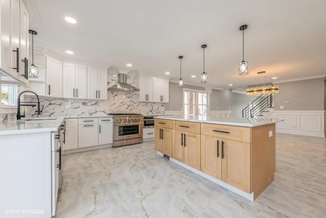 kitchen with wall chimney exhaust hood, sink, a center island, high end stainless steel range oven, and white cabinets