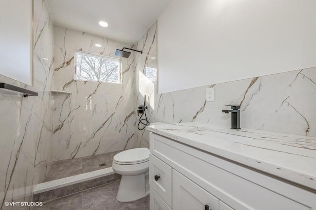 bathroom with a tile shower, vanity, and toilet