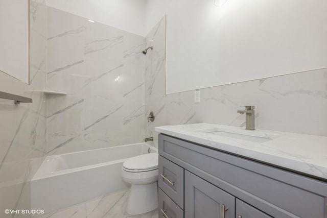 full bathroom with vanity, tile walls, toilet, and tiled shower / bath