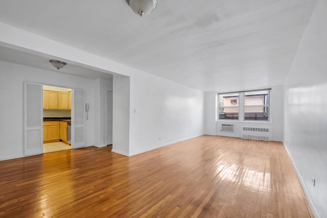 unfurnished living room with radiator heating unit and light hardwood / wood-style floors